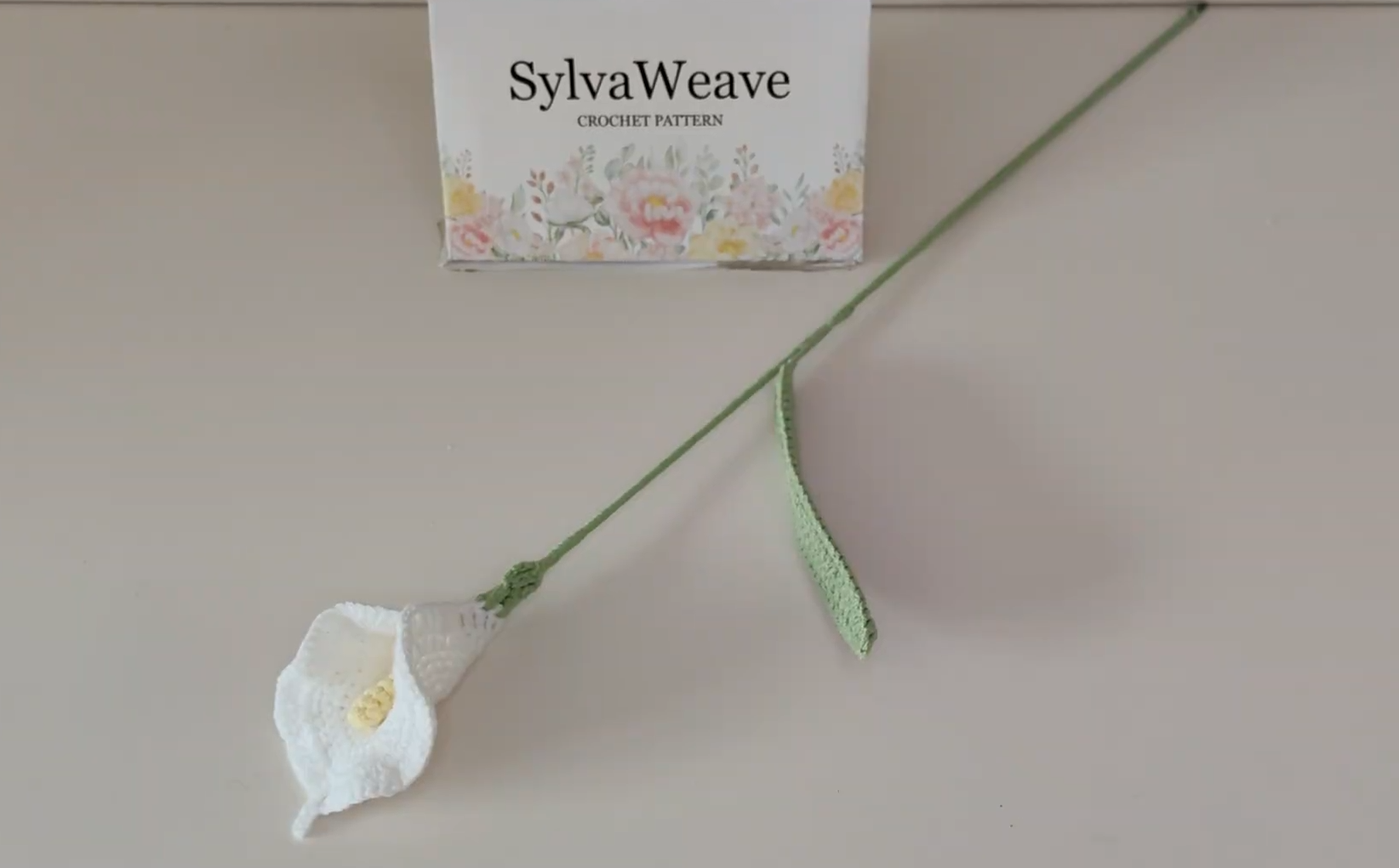 Finished white crochet calla lily with yellow center and green leaf