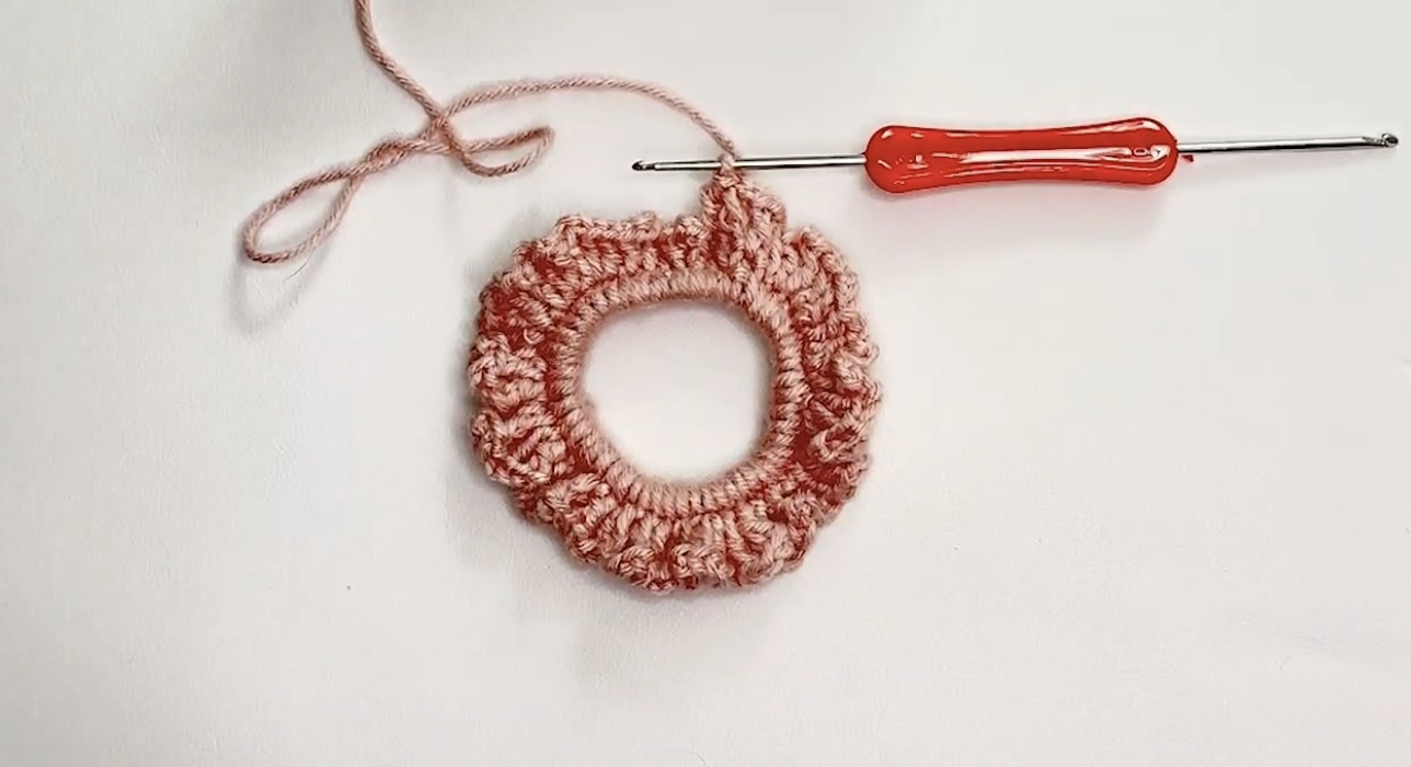 Double crochet and chain spaces around the flower scrunchie in round 2