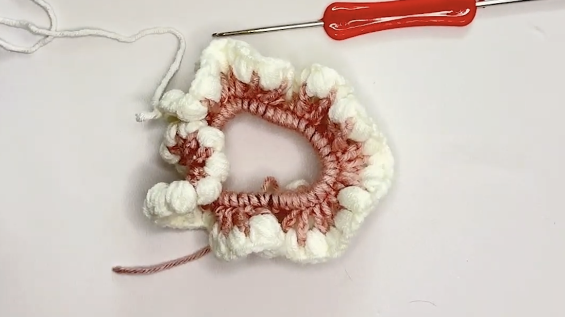 White puff stitches worked into the large chain spaces in round 3