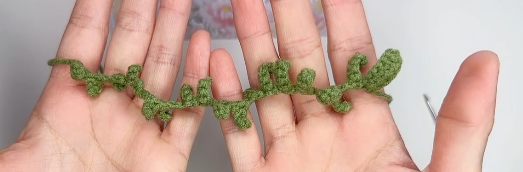 Completed green crochet leafy stem for a lavender flower
