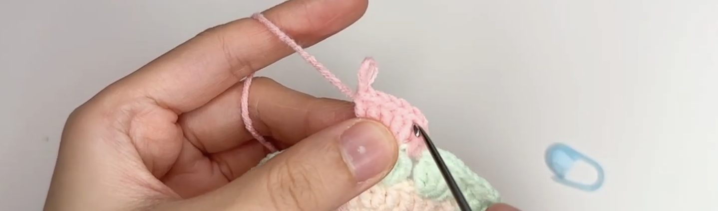 Closing a pink crochet tulip petal on the coaster
