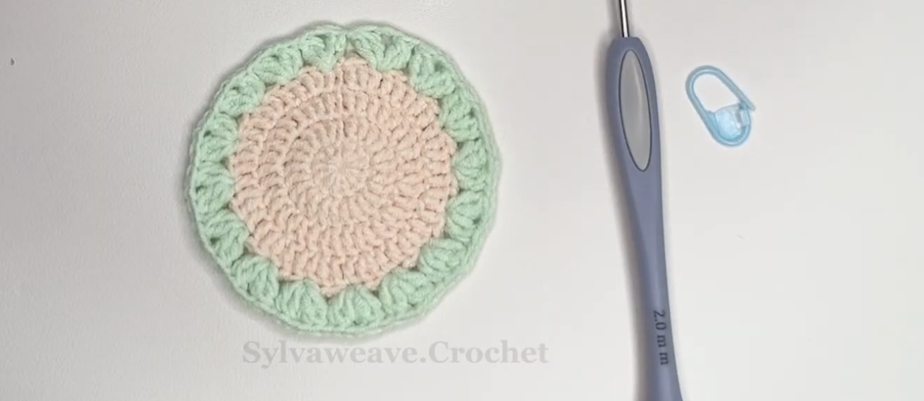 Green leaf clusters around the crochet tulip coaster base